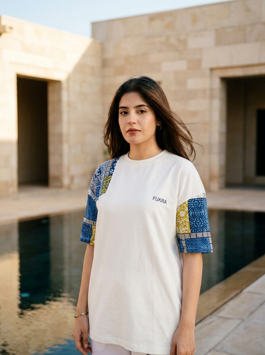 Ivory tee with indigo patchwork sleeves by a reflecting pool